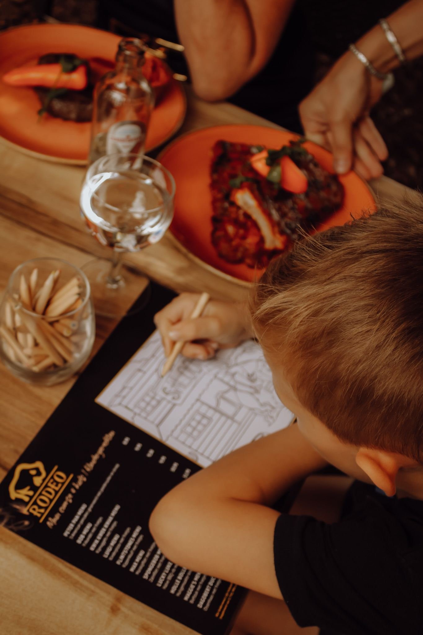 Kind kleurt een placemat naast een bord ribbetjes