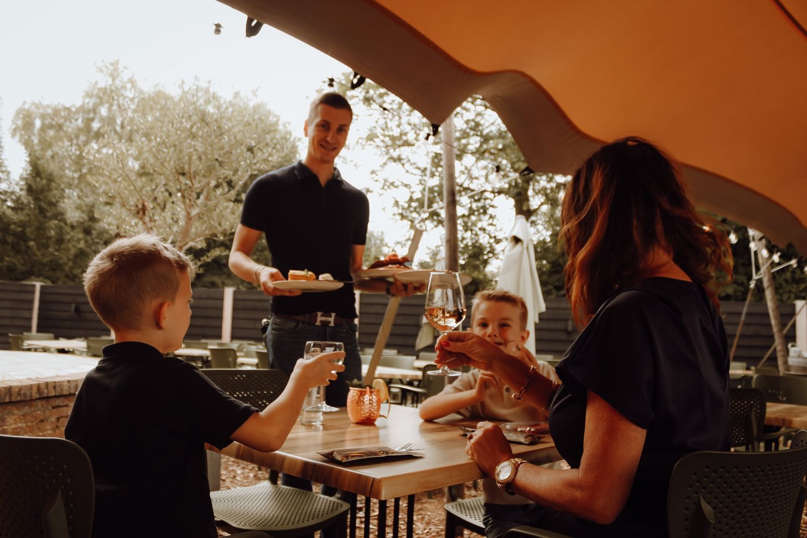 Bediening serveert een familie met kinderen op het terras van Saloon Rodeo
